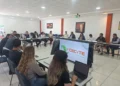 Grupo de personas en reunión en una sala moderna con pantallas y laptops, discutiendo temas educativos en Michoacán.