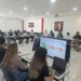 Grupo de personas en reunión en una sala moderna con pantallas y laptops, discutiendo temas educativos en Michoacán.