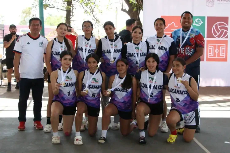 Grupo de jugadoras de voleibol con medallas y uniformes en evento deportivo en Michoacán o Jalisco.