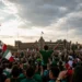 Multitud de personas en una manifestación en la Ciudad de México, ondeando banderas mexicanas bajo un cielo nublado.