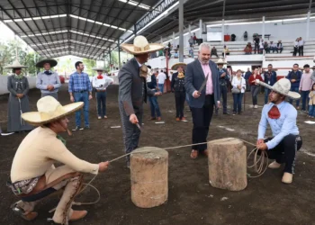 Personas participando en una competencia tradicional de tiro con cuerda en un evento cultural en Michoacán, con espectadores.