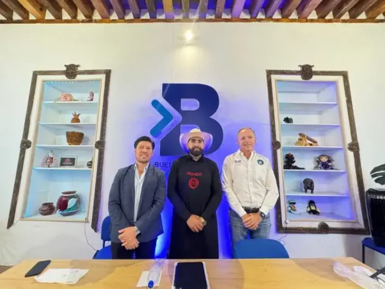 Tres hombres en una sala con estanterías llenas de objetos decorativos y un logo grande en la pared.