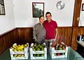 Pareja sonriendo con cajas de frutas en un establecimiento.