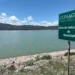 Represa en Michoacán con señal de zona de reductores de velocidad y paisaje montañoso al fondo.