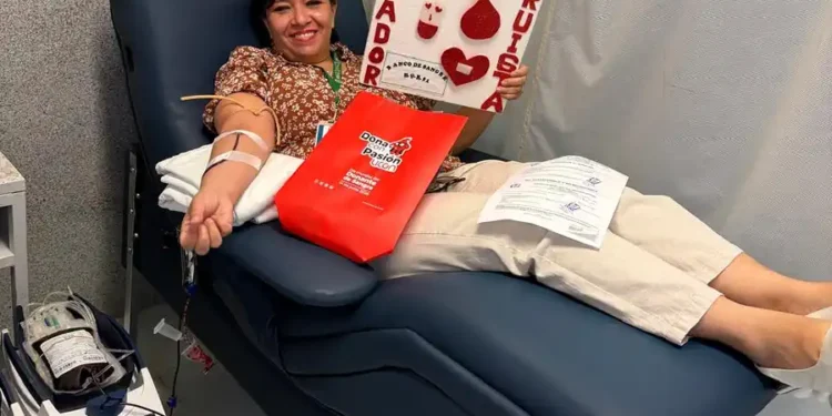 Mujer dona sangre en hospital, participando en campaña solidaria con cartel de "Soy altruista" y corazones rojos.
