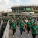Aficionados con camisetas verdes ingresan al Estadio Azteca para apoyar a la selección mexicana.