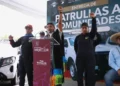 Hombres y mujeres levantan el puño en señal de unidad durante evento de entrega de patrullas.