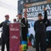Hombres y mujeres levantan el puño en señal de unidad durante evento de entrega de patrullas.