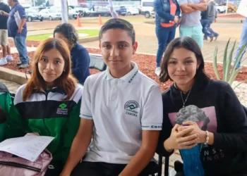 Jóvenes en una actividad escolar en Michoacán, participando en un evento al aire libre con otros estudiantes y docentes en un.