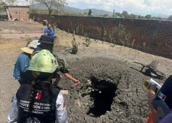 Personal de protección civil inspecciona un hundimiento en el suelo tras un sismo en Michoacán.