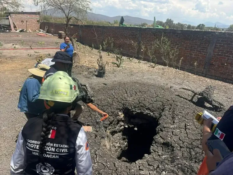 Personal de protección civil inspecciona un hundimiento en el suelo tras un sismo en Michoacán.