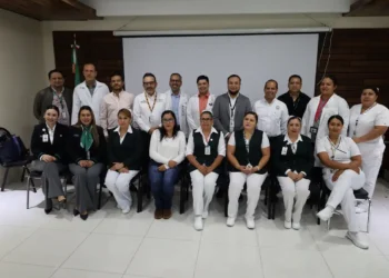 Grupo de profesionales de la salud en capacitación en Zamora, Michoacán, con fondo de pantalla y bandera mexicana.
