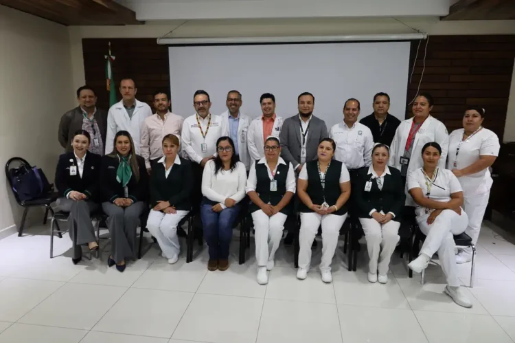 Grupo de profesionales de la salud en capacitación en Zamora, Michoacán, con fondo de pantalla y bandera mexicana.
