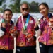 Dos jóvenes deportistas mexicanas y un entrenador posan con medallas en torneo de voleibol de playa en Jalisco.
