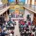 Reunión de comerciantes y autoridades en un patio colonial con murales coloridos en Pátzcuaro.