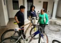 Personas conversando junto a bicicletas en un espacio cubierto.