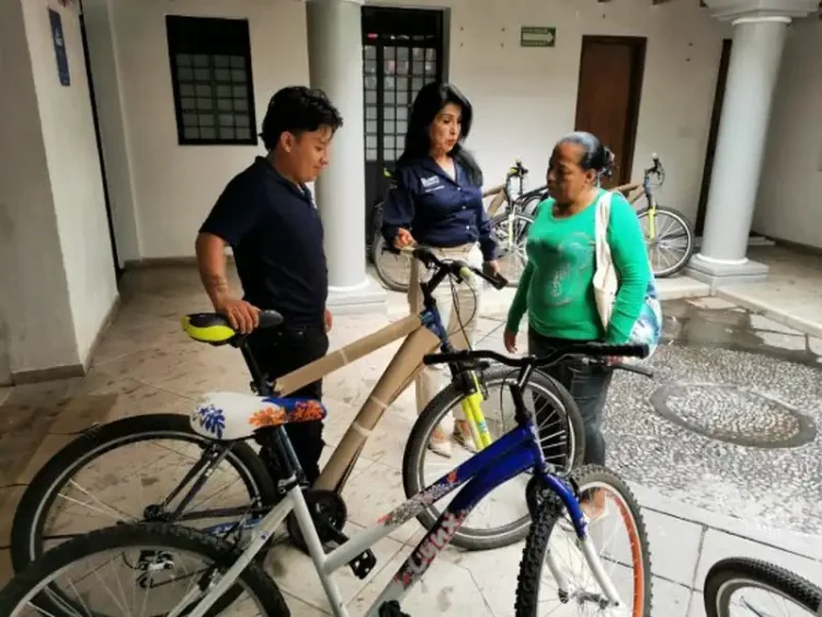 Personas conversando junto a bicicletas en un espacio cubierto.