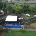 Paneles solares instalados en un área de cultivo con vehículos y árboles alrededor.