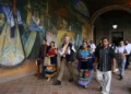 Personas caminando frente a mural colorido en evento cultural en Michoacán.
