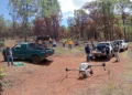 Drones sobre campo de tierra con vehículos y personas en Michoacán durante siembra de semillas.