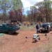 Drones sobre campo de tierra con vehículos y personas en Michoacán durante siembra de semillas.