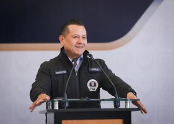 Torres Piña en conferencia de prensa, vestido con uniforme de fiscalía, sonriendo mientras habla frente a micrófonos.