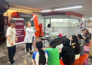 Estudiantes participando en un taller de ciencia en la Universidad Nacional de Rosario, con una instructora explicando concep.