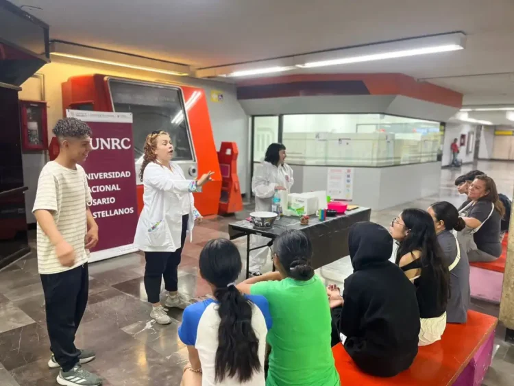 Estudiantes participando en un taller de ciencia en la Universidad Nacional de Rosario, con una instructora explicando concep.