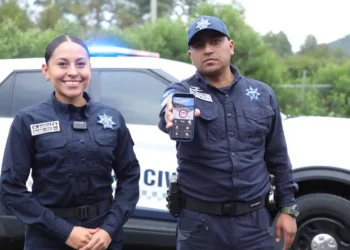 Policías muestran un teléfono móvil con una aplicación de bloqueo de llamadas de extorsión en Michoacán.