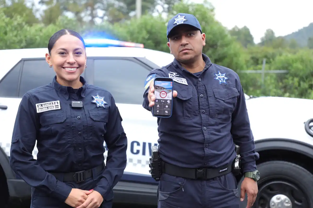 Policías muestran un teléfono móvil con una aplicación de bloqueo de llamadas de extorsión en Michoacán.