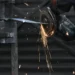 Trabajador usando amoladora para cortar metal en un entorno industrial, con chispas y luz tenue en el fondo.