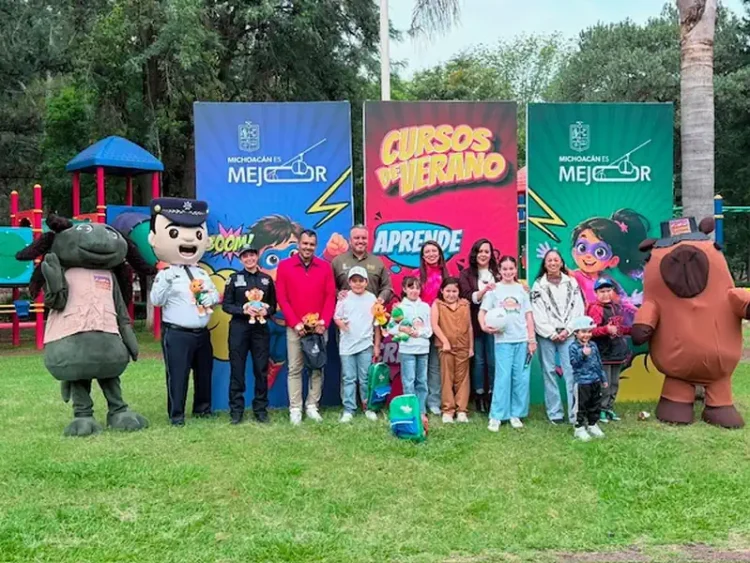 Niños y adultos disfrutan actividades en parque con personajes de caricaturas y banners promocionales de cursos de verano.