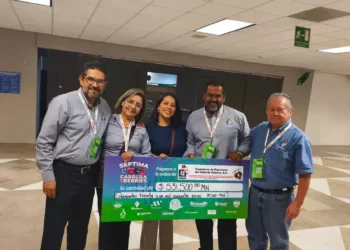 Grupo de cinco personas sosteniendo un cheque grande en un espacio interior, celebrando donativo récord de Aneberries.