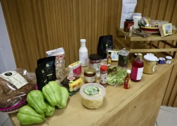 Variedad de productos orgánicos en una mesa de madera, incluyendo verduras, frascos y paquetes de alimentos naturales.