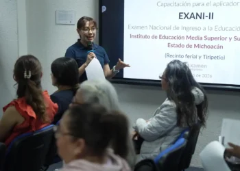 Mujer dando capacitación en un aula con pantalla para examen de ingreso a Normales en Michoacán.