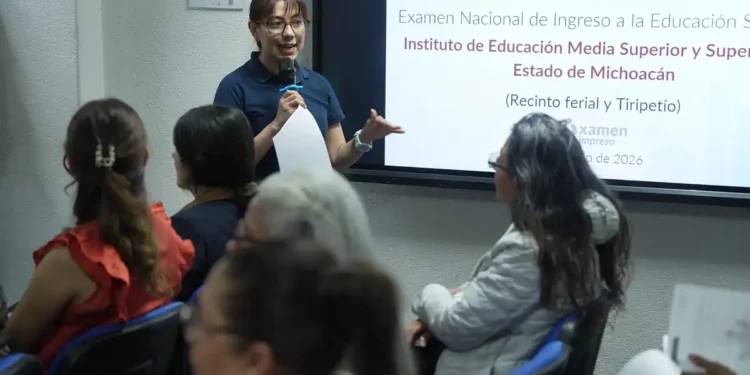 Mujer dando capacitación en un aula con pantalla para examen de ingreso a Normales en Michoacán.