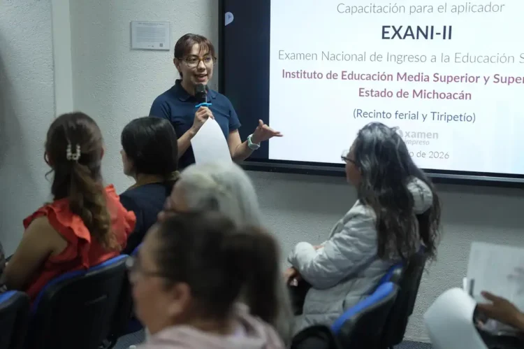 Mujer dando capacitación en un aula con pantalla para examen de ingreso a Normales en Michoacán.