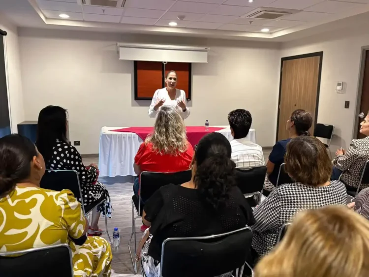 Mujer dando conferencia en taller de tanatología en Zamora, con asistentes atentos en sala moderna.