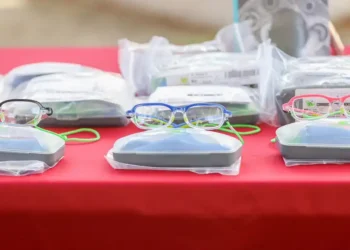 Lentes de diferentes colores y estilos en una mesa con empaques y accesorios para estudiantes en Michoacán.