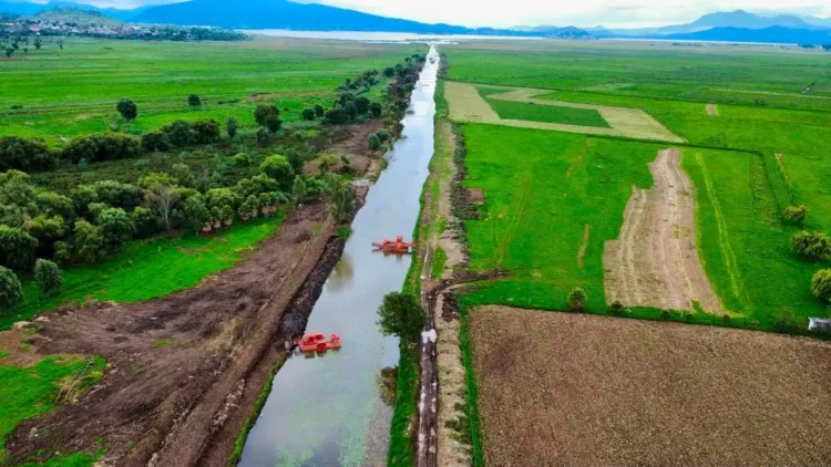 Canal de Erongarícuaro con agua clara y vegetación verde a sus lados, en un día soleado.
