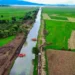 Canal de Erongarícuaro con agua clara y vegetación verde a sus lados, en un día soleado.