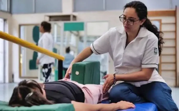 Fisioterapeuta ayuda a paciente en sesión de rehabilitación en clínica del IMSS Michoacán.