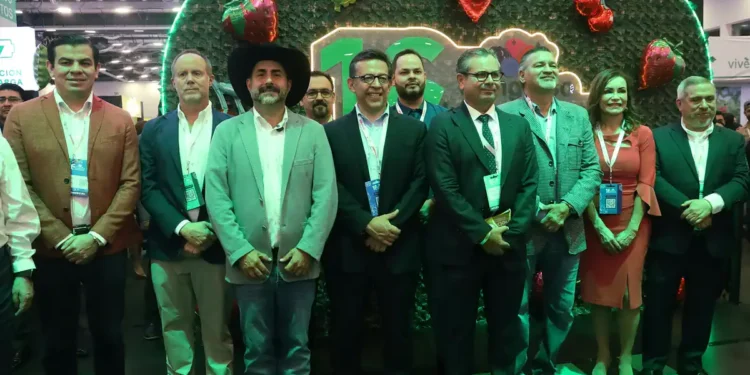 Funcionarios y empresarios en stand de berries en feria agrícola en Jalisco.