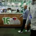 Hombres en el Congreso Internacional de Berries en Jalisco, con stand y asistentes en el fondo.