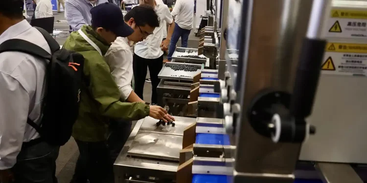 Jóvenes y adultos observan maquinaria moderna en feria de tecnología agrícola en Jalisco.