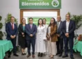 Grupo de profesionales en un evento de reconocimiento en un espacio cerrado con decoraciones verdes y mesas con manteles.