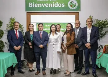 Grupo de profesionales en un evento de reconocimiento en un espacio cerrado con decoraciones verdes y mesas con manteles.