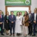 Grupo de profesionales en un evento de reconocimiento en un espacio cerrado con decoraciones verdes y mesas con manteles.