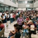 Personas esperando en fila en un hospital público en Michoacán, muchas con mascarillas y en interiores con luz natural.