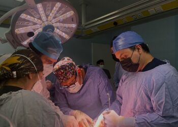 Equipo médico realiza trasplante de órganos en quirófano con iluminación especializada y personal en bata y mascarillas.